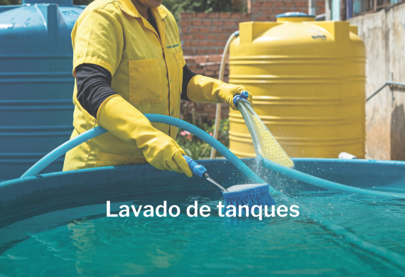 Mujer con indumentaria de seguridad amarilla lavando un tanque contenedor de agua.